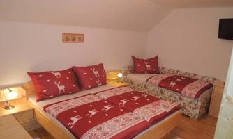 A cozy bedroom with two beds and red bed covers. The room is bright and decorated in a modern style.
