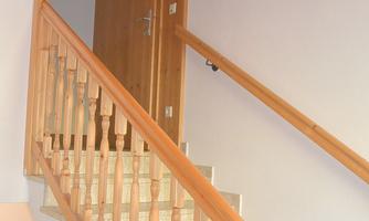 A staircase with a wooden railing leads upwards. In the background, a wooden door is visible.