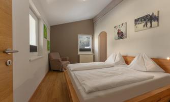 A modern bedroom with a double bed and a comfortable armchair. Pictures hang on the walls that create a cozy atmosphere.
