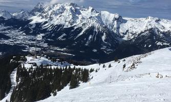 An impressive wintry mountain landscape with snow-covered peaks. In the foreground, there are snow-covered slopes and coniferous trees.