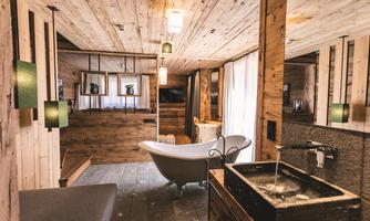 A modern bathroom with a freestanding bathtub and wood paneling. The space is bright and inviting, with decorative lights and a stylish sink.