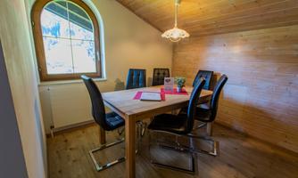 A cozy room with a wooden table and black chairs. A window provides plenty of daylight and an inviting atmosphere.