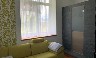 A modern living room with a yellow sofa and a large window. There is a stylish stone facade on the wall.