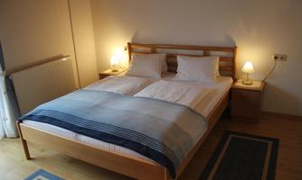 A cozy bedroom with a double bed and two bedside tables. The warm light sources create an inviting atmosphere.