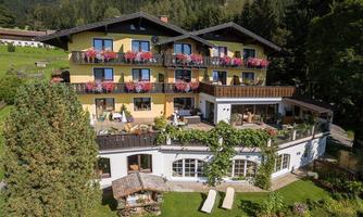 A charming hotel with colorful flowers on the balconies. The surroundings are green and invite relaxation.