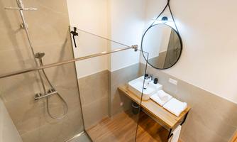 A modern bathroom with a shower and a sink. The room has bright tiles and wooden details.