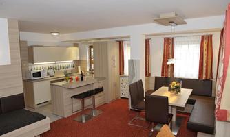 A modern, cozy apartment with a kitchenette and a dining area. Light colors and comfortable furniture create an inviting atmosphere.