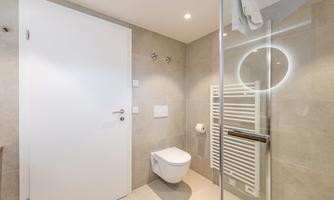 A modern bathroom with a shower and a bright wall design. The room is clean and minimally furnished.