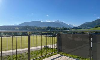 A beautiful view of the mountains and the green landscape from a balcony. The sky is clear and the day is sunny.