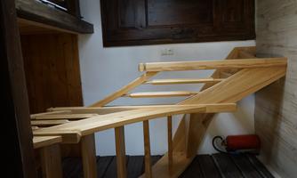 An elegant wooden staircase leads upstairs. In the background, a wooden door can be seen.