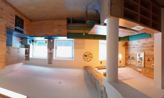 A bright kitchen with wooden details and modern appliances. It features a cozy seating area and large windows that let in plenty of daylight.