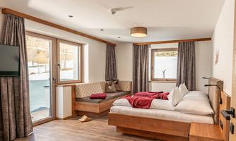 A modern room with a double bed and a cozy seating area. Large windows allow plenty of daylight in and offer a view of the surroundings.