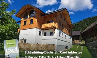 A cozy wooden house in a mountainous landscape under a blue sky. In the foreground, there is a map of the Schladming-Dachstein region.