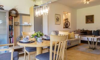 A modern living room with a cozy sofa and a dining table. The room is bright and cheerfully furnished.