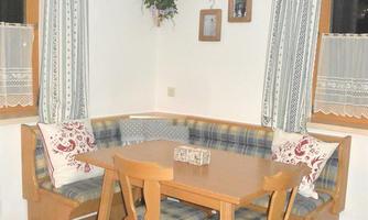 A cozy dining area with a round table and chairs. The walls are adorned with curtains and decorations.
