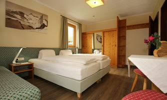 A cozy room with two single beds and a desk. The decor is simple and functional, with a window that lets in natural light.