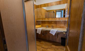 A modern bathroom with wooden walls and two sinks. Towels are ready, and a large mirror is visible.