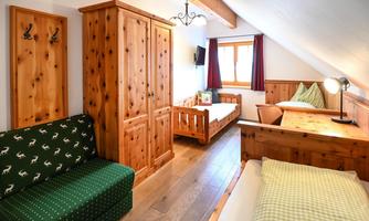 A cozy room with wooden furniture and two beds. The room design is rustic and inviting, perfect for a relaxing stay.
