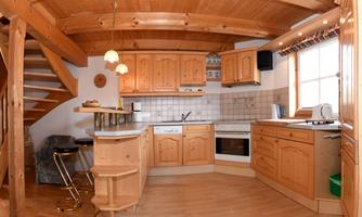 A cozy kitchen with wooden cabinets and a modern stove. The versatile furnishings and the large windows create a bright atmosphere.