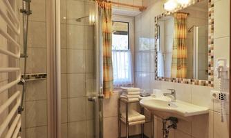 A bright bathroom with a modern shower and a sink. White tiles and large windows create an inviting atmosphere.