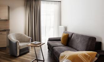 A stylish living room with a gray sofa and a cozy armchair. Large windows let in plenty of light and create an inviting atmosphere.