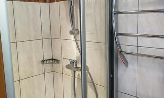 A modern shower with smooth tiles and chrome fixtures. The shower is clean and well-organized with a towel holder.