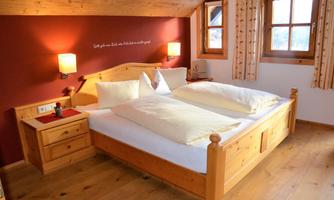 A cozy bedroom with a large wooden bed and soft pillows. The warm colors and wooden design create an inviting atmosphere.