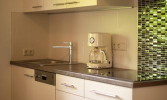 A modern kitchen with bright cabinets and a stylish countertop. The kitchen is equipped with a dishwasher, stove, microwave, cooking pots, plates, bowls, cutlery, and more.