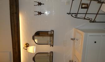 A modern bathroom with two sinks and stylish mirrors. Decorative hooks hang on the wall, and elegant lighting creates a cozy atmosphere.