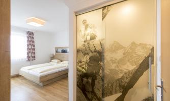 A cozy bedroom with a large bed and natural light. A glass sliding door with a mountain motif for added flair.