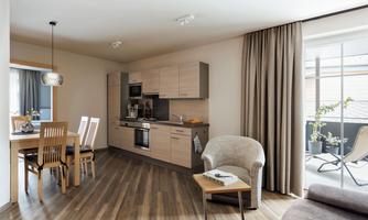 A modern kitchen and living area with wooden flooring. The room is bright and comfortably furnished.