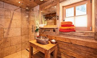 A cozy bathroom with wooden paneling and modern elements. The shower is glass-enclosed and fresh towels are ready.