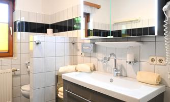 A modern bathroom with an elegant washbasin and a large mirror. The walls are brightly tiled and the decor is in neutral colors.