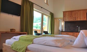 A modern bedroom with a double bed and cozy furnishings. Large windows offer a view of the surrounding nature.