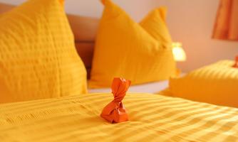 A cozy bed with bright yellow pillows and an orange candy in the center. The warm color scheme creates an inviting atmosphere.