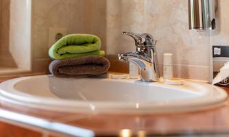 A modern sink with a shiny faucet. On it lie two towels in fresh colors.