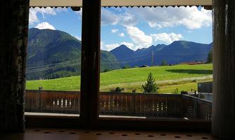 A beautiful view of green meadows and impressive mountains under a blue sky. The scenery is calm and idyllic.
