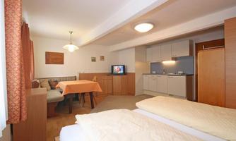 A cozy room with a double bed, a table, and a seating area. The integrated kitchen and the television provide comfort.