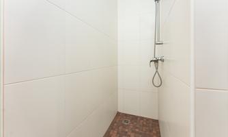 A modern shower cabin with bright walls and a brown floor. The fixture is simply and functionally designed.