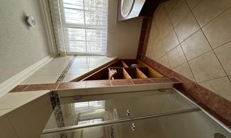 A modern bathroom with a shower and a spacious sink. Bright windows provide plenty of light in the room.