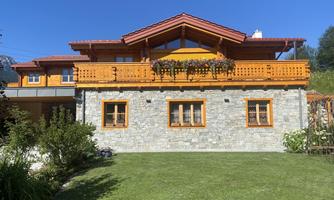 A charming house with a wood and stone facade. The well-kept garden and the sunny facade give the building an inviting character.
