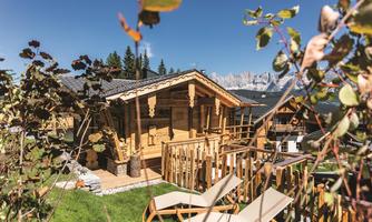 An idyllic wooden house surrounded by trees and mountains. The terrace invites relaxation while the sun shines.