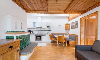 A bright and modern kitchen with a wooden ceiling and a cozy seating area. The space is welcoming and well-furnished.