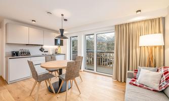 A modern apartment with a bright kitchen and a dining area. Large windows offer a view of the balcony and let in plenty of daylight.