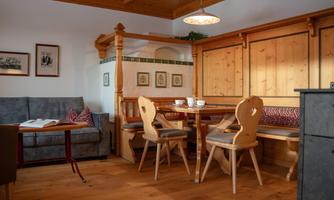 A cozy dining area with panelled wooden walls and a table. The decor is traditional, with a sofa and decorative pictures.