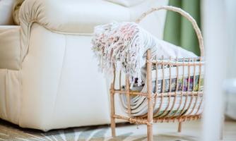 A cozy basket with blankets and magazines stands next to a bright sofa. The room feels inviting and warm.