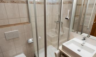 A modern bathroom with shower, washbasin, and toilet. The walls are brightly tiled and the fixtures are functional and stylish.
