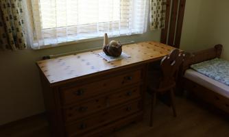 A simple room with a wooden table and a chair. The large window front lets in a lot of light.