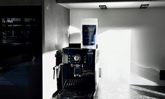 A modern espresso machine stands on a shiny kitchen countertop. The light falls on the machine, creating a beautiful contrast.