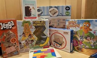 A collection of board games and puzzles on a table. The games are colorful and include classic and creative games for kids and family.